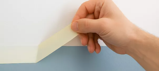 hand som drar av målartejp från vägg utan att skada färg